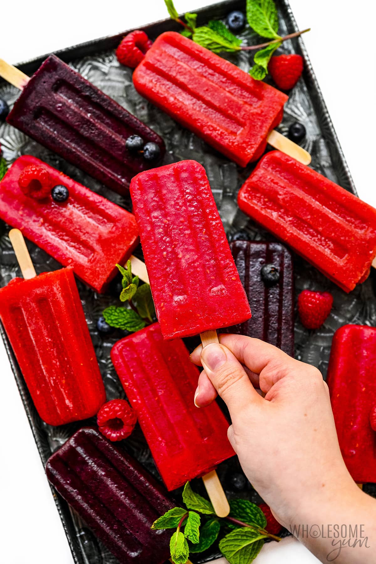 Hand holding one popsicle up from the rest.