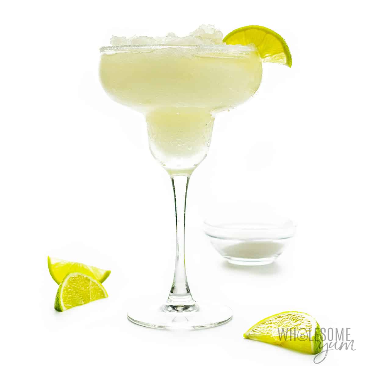 Skinny margarita in glass with lime wedges.